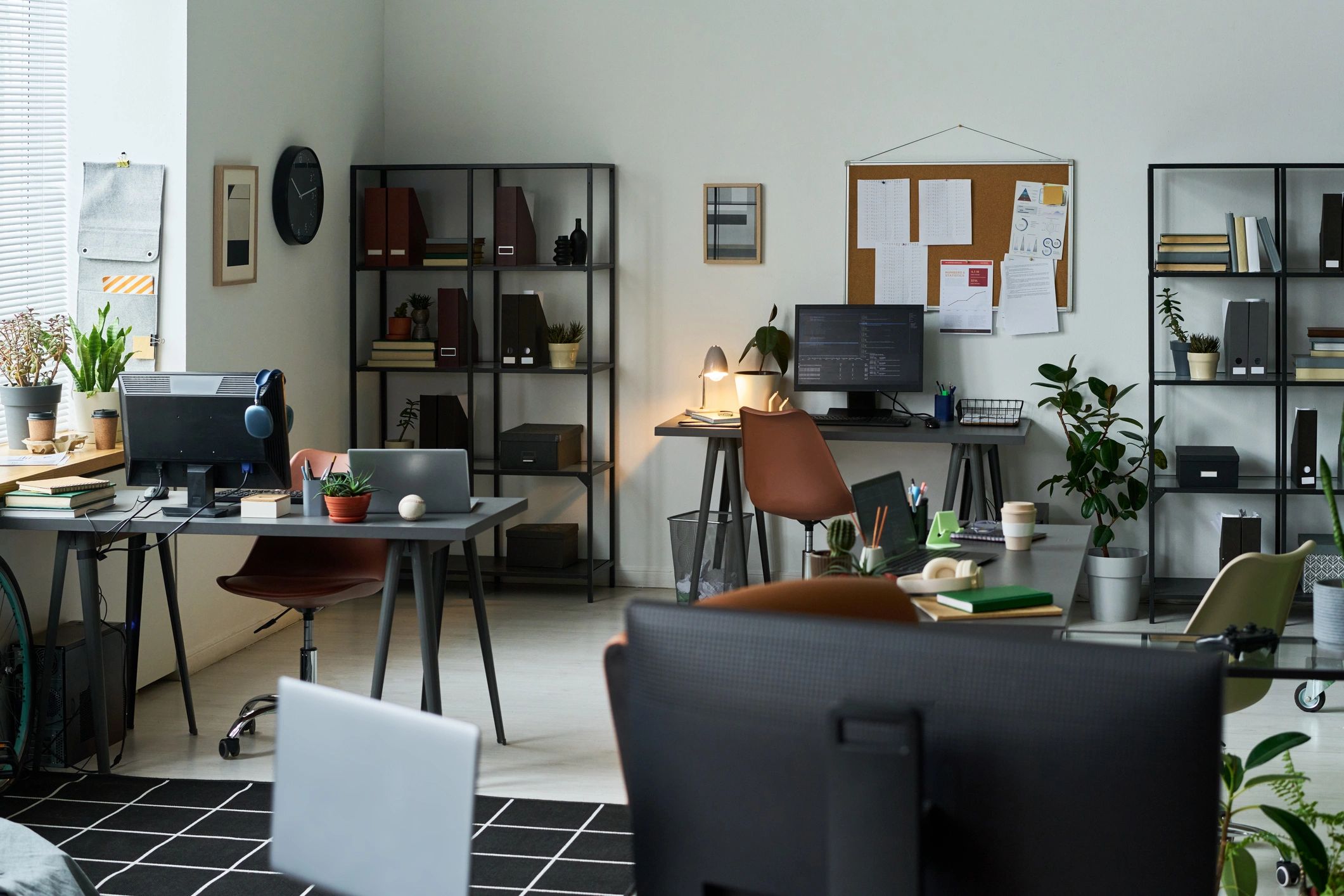 Interior design studio workspace with desks, shelving, and plants